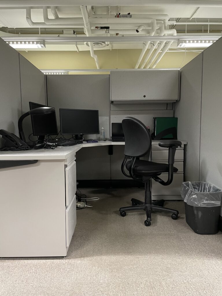 An office cubicle with chair and computer monitors